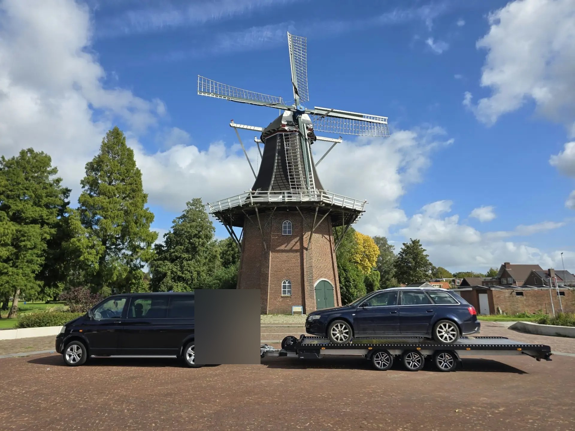 Personenauto op een autotrailer bij een molen